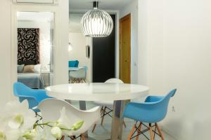 un comedor con una mesa blanca y sillas azules en Santa Cruz Apartments, en Málaga