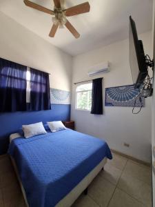a bedroom with a blue bed and a ceiling fan at Mini Apartamento Giada in Nicoya