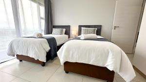 1 dormitorio con 2 camas con sábanas blancas y ventana en Umhlanga Cosy Apartment, en Durban 23 fotos más
