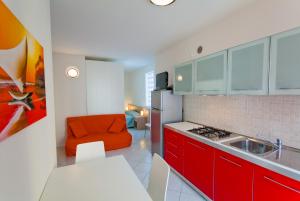 a kitchen with red cabinets and an orange chair at Residence Al Mare - Monolocale con Terrazza - Agenzia Cocal in Caorle