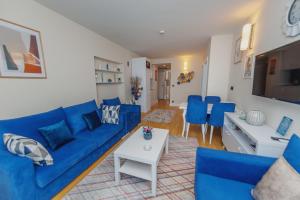 ein Wohnzimmer mit einem blauen Sofa und blauen Stühlen in der Unterkunft P A N O R A M A ORBi city APARTHOEl SEA VIEW in Batumi
