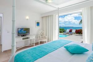 a bedroom with a bed with a television and a balcony at Seafront sunset & beach access in Saint Martin