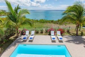 a swimming pool with lounge chairs and the ocean at Seafront sunset & beach access in Saint Martin