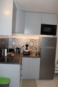 una cucina con armadi bianchi e frigorifero in acciaio inossidabile di Studio indépendant proche Paris a Chennevières-sur-Marne
