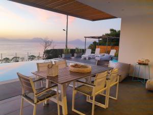 a dining room with a table and chairs and the ocean at Villa Titi in Kamínia