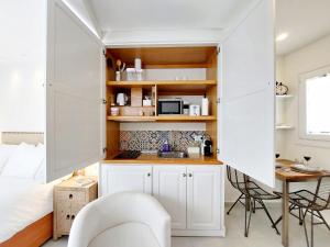 a small kitchen with white cabinets and a white chair at Casita de la Suerte in Medina Sidonia