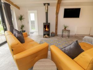 a living room with two yellow couches and a fireplace at Windy Willows in Okehampton