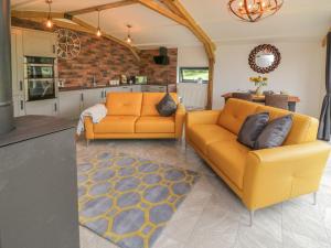 a living room with two orange couches and a kitchen at Windy Willows in Okehampton