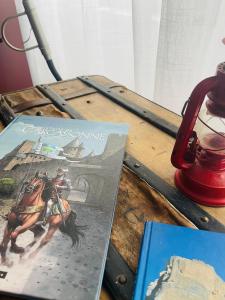 カルカソンヌにあるLa Belle Etape à Carcassonneの二冊の本と赤いランプのテーブル