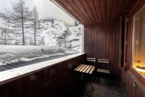 Habitación con banco y ventana cubierta de nieve. en Erza Uno - Cervinia Ski in Ski out Apartment, en Breuil-Cervinia