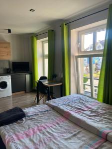 シュチェチンにあるApartamenty Bezrzeczeのベッドルーム(緑のカーテン、ベッド1台、テーブル付)