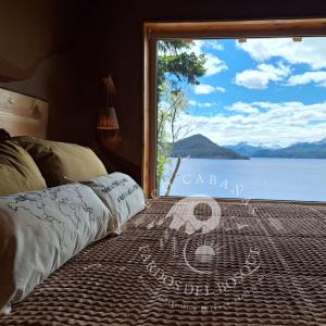 a bedroom with a large window with a view of the water at Eco Cabañas Fardos del Bosque in San Carlos de Bariloche