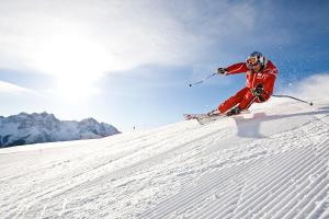 a man is skiing down a snow covered slope at CURUNA Hotel-Garni in Scuol