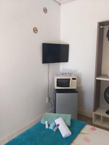 a room with a microwave and a bed with towels at Kitnet espaçosa e bem localizada - Próximo ao lago e centro de eventos in Cascavel