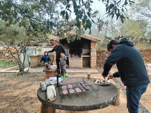 a group of people standing around a table with a grill at Mas de Paco, Chimenea, barbacoa y piscina in Vall dʼAlba