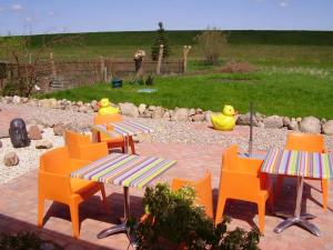 a patio with orange chairs and tables and a yard at Gäste-Zimmer am Elberadweg in Damnatz