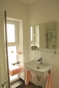 a white bathroom with a sink and a mirror at Gäste-Zimmer am Elberadweg in Damnatz