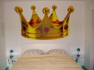 a crown hanging on a wall above a bed at Gäste-Zimmer am Elberadweg in Damnatz