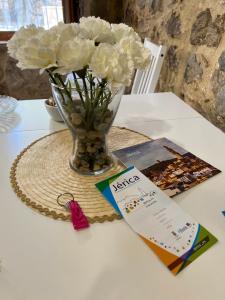 um vaso de flores brancas sobre uma mesa com um cartão em Apartamento Rural Piedra em Jérica