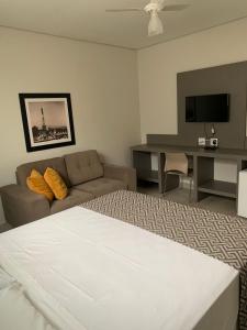 ein Wohnzimmer mit einem Bett und einem Sofa in der Unterkunft Hotel Ouro Verde in Três Pontas