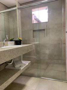 y baño con ducha acristalada y lavamanos. en Hotel Ouro Verde en Três Pontas