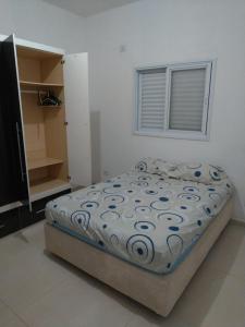 ein Schlafzimmer mit einem Bett in einem weißen Raum in der Unterkunft Casa ampla com fácil acesso as Praias e Shopping in Caraguatatuba