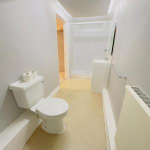 a white bathroom with a toilet and a shower at The Elder Grove Epsom in Epsom
