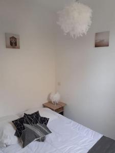 una camera da letto con un letto con cuscini bianchi e neri di VILLA Face à la Mer Sur le Sable 6 CLIM A L'ETAGE a Le Barcarès