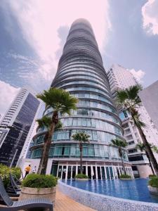 un edificio alto con palmeras delante en Vortex Suites Klcc By SALEH, en Kuala Lumpur