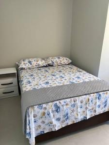 a bedroom with a bed with a floral comforter at Caminho do Mar Ap 4 in Governador Celso Ramos