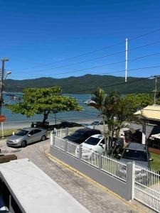 a group of cars parked in a parking lot near the water at Caminho do Mar Ap 4 in Governador Celso Ramos