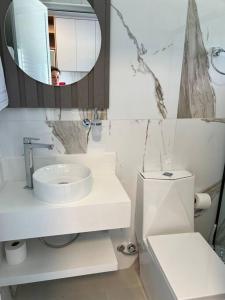 a bathroom with a sink and a mirror and a toilet at Caminho do Mar Ap 4 in Governador Celso Ramos