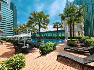 a pool with benches and palm trees in a city at Vortex Suites Klcc By SALEH in Kuala Lumpur