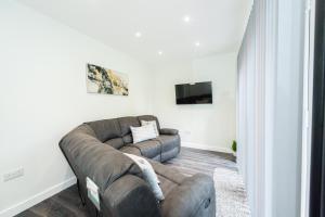 a living room with a brown couch and a tv at Modern 4-Bed Retreat with Garden in Manchester