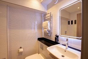 uma casa de banho com um lavatório, um WC e um espelho. em City Sleeper at Royal National Hotel em Londres
