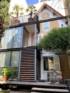 une maison avec de grandes fenêtres et une table sur une terrasse couverte dans l'établissement Architect house - 20min Paris - SUMMER & Olympics 2024, à Courbevoie