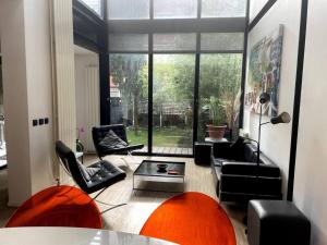 Elle comprend un salon doté d'un mobilier noir et orange et d'une grande fenêtre. dans l'établissement Architect house - 20min Paris - SUMMER & Olympics 2024, à Courbevoie