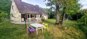 a table and chairs in front of a house at La maison du Diplo : Forêt, sentiers et grimpe in Le Vaudoué