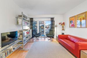 Appartement aan Zee Oostende في أوستند: غرفة معيشة مع أريكة حمراء وكرسيين