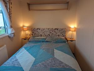 a bed in a small room with two lamps at Seasons Caravan 3 bedroom Haven Littlesea in Weymouth