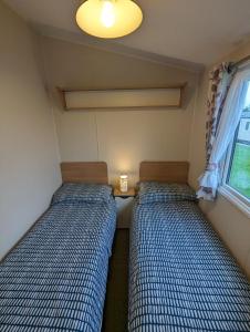 two beds in a small room with a window at Seasons Caravan 3 bedroom Haven Littlesea in Weymouth