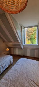 a attic bedroom with a large window and two beds at La maison du Diplo : Forêt, sentiers et grimpe in Le Vaudoué