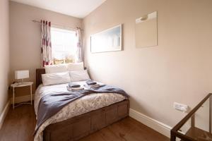 a small bedroom with a bed with a window at Family home in central Guildford with Parking in Guildford
