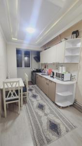 a kitchen with white cabinets and a table and a rug at APARTMENT “NOVZA” in Tashkent