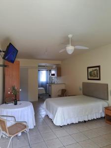 a bedroom with a bed and a table and a tv at Velho Estaleiro Apartamentos por Temporada in São Lourenço do Sul