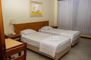 Habitación de hotel con 2 camas y mesa en Hotel Radar, en Gravataí