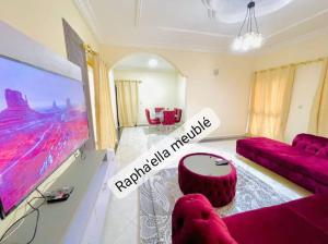 a living room with a red couch and a table at Appartement Rapha'ella Meublé in Yaoundé