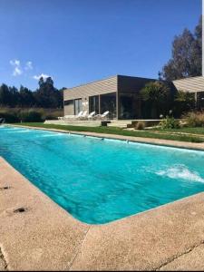 a large blue swimming pool in front of a house at Bello departamento Algarrobo in Algarrobo
