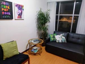 a living room with a black couch and a table at Flat Perto de Tudo na Savassi in Belo Horizonte