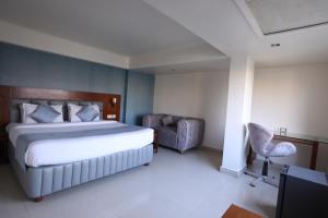 um quarto com uma cama, uma cadeira e uma televisão em Eastin Hotels em Hyderabad